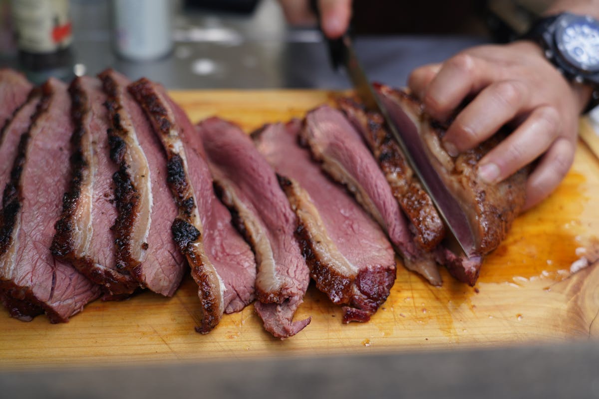 Close-up of smoked brisket with dark crusty bark showing Maillard browning and rub texture